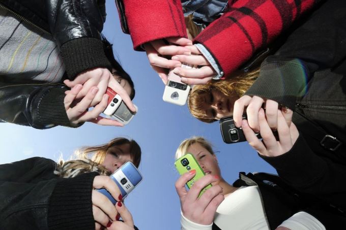 AFP/Scanpix nuotr./Jaunimas naudojasi mobiliaisiais telefonais