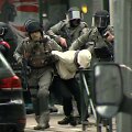 Belgijos policininkai veda penktadienį sulaikytą asmenį.