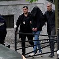 Serbų policijos pareigūnai palydi įtariamąjį / OLIVER BUNIC / AFP