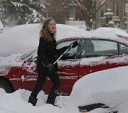 Detroite merginta valo sniegą nuo automobilio.