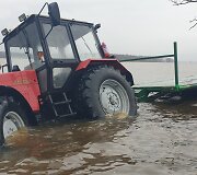 Traktoriumi važiavę vyrai nuvažiavo nuo patvinusio kelio į griovį.