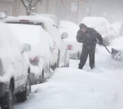 Čikagoje vyras prie savo automobilio kasa sniegą.