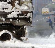 Vaikai bėga pro sudegusį automobilį.