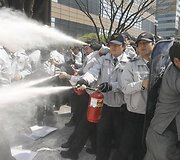 Policininkai gesina demonstrantų padegtas &Scaron;.Korėjos simbolius.