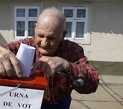 Senukas meta rinkimų lapelį į mobilią balsavimo dėžutę.