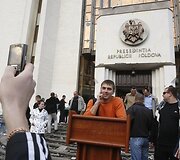 Valdžią ironizuojantis jaunuolis pozuoja prie parlamento.