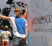 Žmonės pasira&scaron;inėja ant Michaelo Jacksono plakato.