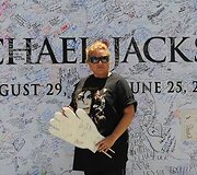 Žmonės pasira&scaron;inėja ant Michaelo Jacksono plakato.