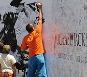 Žmonės pasira&scaron;inėja ant Michaelo Jacksono plakato.