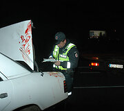 Policininkas apžiūri sudaužytą automobilį