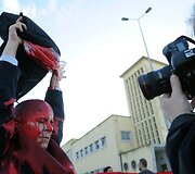 Protestuotojai apsipylė raudonais dažais.