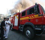 Policininkas stovi prie gaisrininkų ma&scaron;inos.
