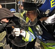 Policininkas ramina siautėjantį demonstrantą.