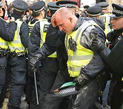 Sužeistam pareigūnui padeda kolega.