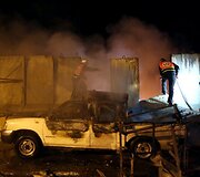 Palestiniečiai prie degančio automobilio, į kurį pataikė Izraelio raketa