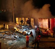 Palestiniečiai prie degančio automobilio, į kurį pataikė Izraelio raketa