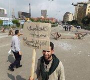 Protestuotojas laiko plakatą, ant kurio užra&scaron;yta: &bdquo;Kodėl kariuomenė mus puola? Gal mes esame Libijoje?&ldquo;