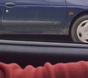 Vienuolė, prie vairo skaitanti laikra&scaron;tį. I&scaron;siliejusių ratų vaizdas byloja, kad buvo fotografuojamas važiuojantis automobilis.