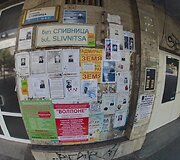 Ant pastato sienų i&scaron;kabinti lapai su čia mirusių žmonių nuotraukomis ir nekrologais