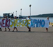 Grįžtantis burlaivis pasitiktas su plakatais.