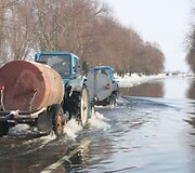 Traktoriai skrodžia apsemtą kelią. 
