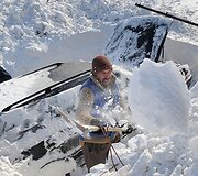 Vyrai atkasinėja apsnigtą automobilį.
