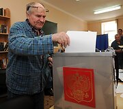 Vyras į balsadėžę deda balsalapį. 