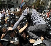 Protestuotoja lipa per policininkų galvas.