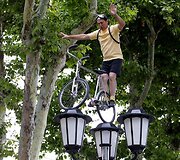 &bdquo;Tour de France&ldquo; dviratininkų lenktynių gerbėjas rodo triukus ant gatvės &scaron;viestuvų.