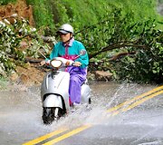 Apsemtu keliu važiuoja vyras su motoroleriu.