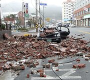 Vėjo ir stiprios liūties neatlaikiusi dalis sienos nugriuvo ant automobilio.