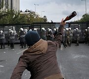 Protestuotojas meta butelį į policininkus.