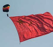 Su didžiule Kinijos vėliava besileidžiantis para&scaron;iutistas
