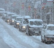 Automobiliai apsnigtoje gatvėje
