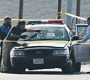 Įvykio tyrėjai apžiūri policijos automobilį, kuriame buvo nu&scaron;autas policininkas.