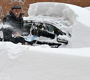 Vyras nuo automobilio valo sniegą.