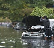 Vyras prie apsemto automobilio