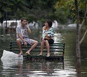 Vietos gyventojai sėdi ant apsemto suoliuko