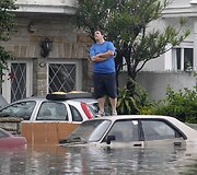 Vyras ant apsemto automobilio stogo