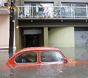 Vyras balkone žiūri į apsemta automobilį.