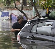 Vyras prie apsemto automobilio