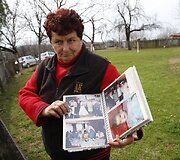 Moteris rodo nuotraukų albumą su kaimo gyventojais