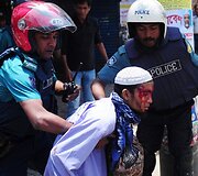 Policininkai veda sužeistą islamistų protestuotoją.