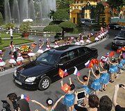 Mergaitės su Rusijos ir Vietnamo vėliavomis mojuoja atvykstančiam Vladimirui Putinui