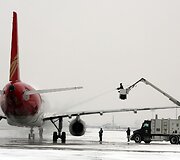 Harbino oro uoste valomi apledėję lėktuvo sparnai.