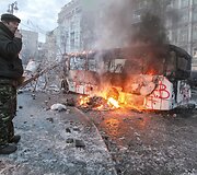 Protestuotojas prie sudegusio autobuso Kijeve