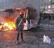Protestuotojas prie sudegusio autobuso Kijeve