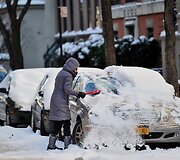Niujorke moteris valo sniega nuo automobilio.