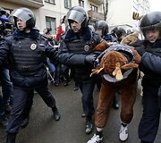 Policininkai veda sulaikytą protestuotoją.