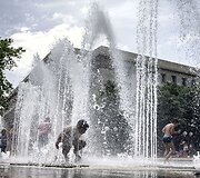 Vaikai kar&scaron;tą vasaros dieną vėsinasi fontane